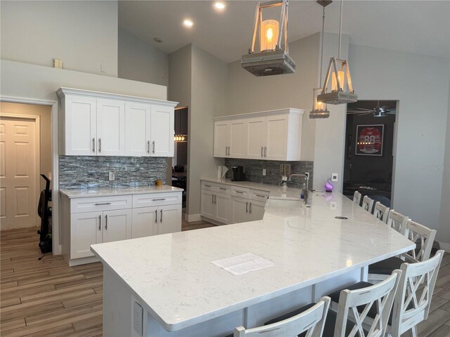 4749 Stoneview Cir, Oldsmar, FL 34677 - kitchen featuring a sink, high vaulted ceiling, a peninsula, backsplash, and white cabinets