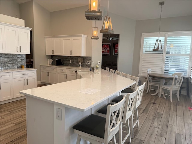 4749 Stoneview Cir, Oldsmar, FL 34677 - kitchen featuring decorative backsplash, a peninsula, white cabinets, a sink, and light wood-style flooring