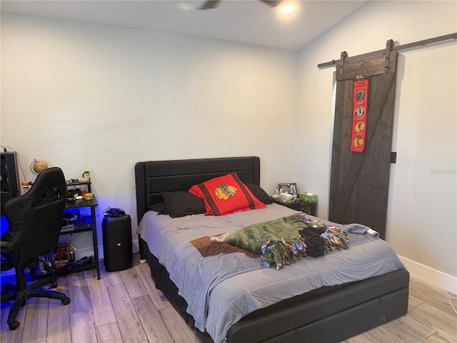 4749 Stoneview Cir, Oldsmar, FL 34677 - bedroom featuring a barn door, wood finished floors, and baseboards