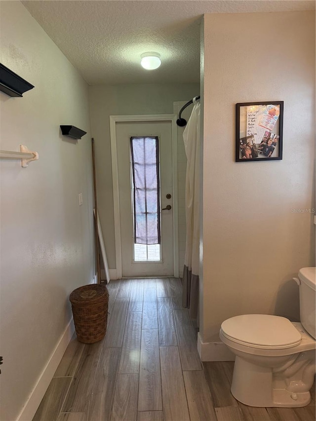 4749 Stoneview Cir, Oldsmar, FL 34677 - full bath featuring a textured ceiling, toilet, wood finished floors, baseboards, and curtained shower