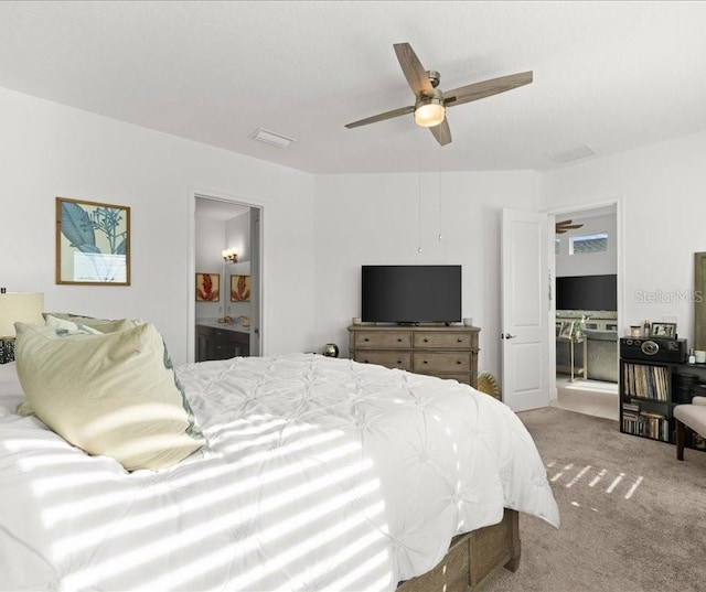 carpeted bedroom with ensuite bathroom, visible vents, and a ceiling fan