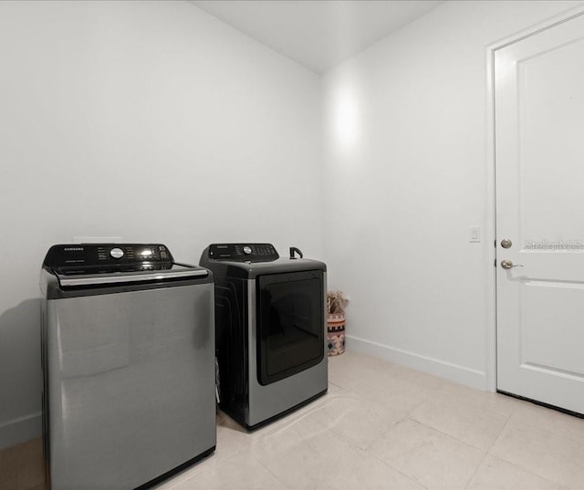 washroom featuring baseboards, separate washer and dryer, and laundry area