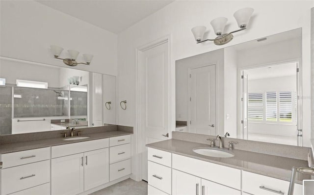 full bath featuring two vanities, a tile shower, and a sink