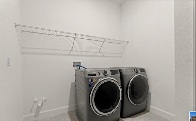 clothes washing area featuring baseboards, washer and clothes dryer, and laundry area
