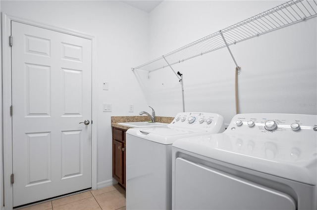 laundry room featuring a sink, washer and clothes dryer, cabinet space, and light tile patterned floors