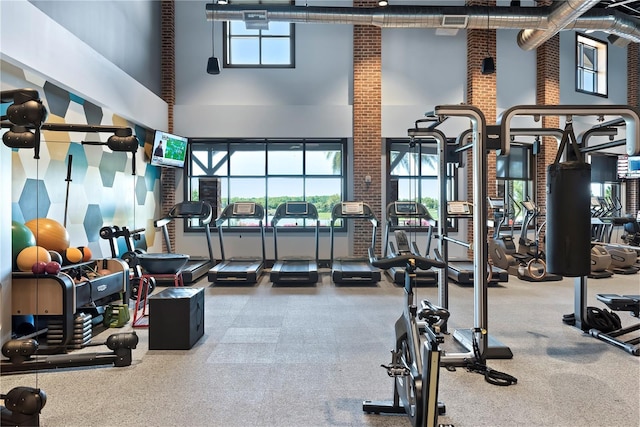workout area featuring brick wall and a towering ceiling