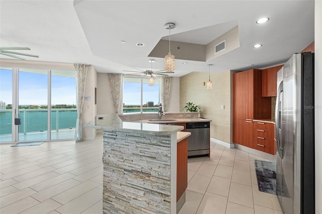 241 Riverside Dr Unit 902, Holly Hill, FL 32117 - kitchen with a sink, brown cabinetry, light tile patterned flooring, ceiling fan, and appliances with stainless steel finishes