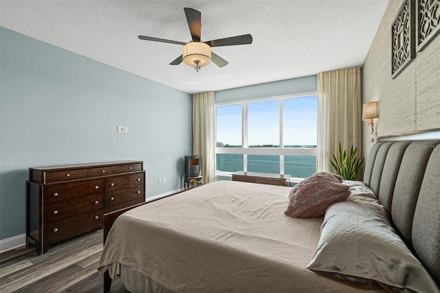 241 Riverside Dr Unit 902, Holly Hill, FL 32117 - bedroom with a ceiling fan, wood finished floors, a textured ceiling, a water view, and baseboards