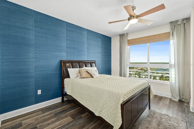 241 Riverside Dr Unit 902, Holly Hill, FL 32117 - bedroom featuring wallpapered walls, dark wood-style floors, a ceiling fan, an accent wall, and baseboards