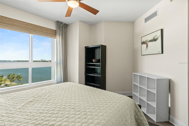 241 Riverside Dr Unit 902, Holly Hill, FL 32117 - bedroom with visible vents, a water view, dark wood-type flooring, baseboards, and ceiling fan