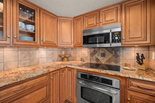 kitchen featuring light stone countertops, stainless steel appliances, and decorative backsplash