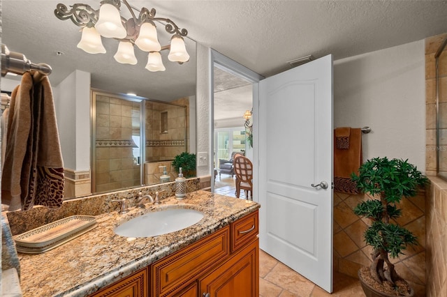 bathroom featuring an inviting chandelier, a shower stall, vanity, visible vents, and a textured ceiling