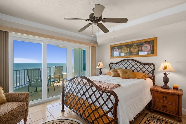 bedroom with a ceiling fan, access to outside, a water view, and stone tile flooring