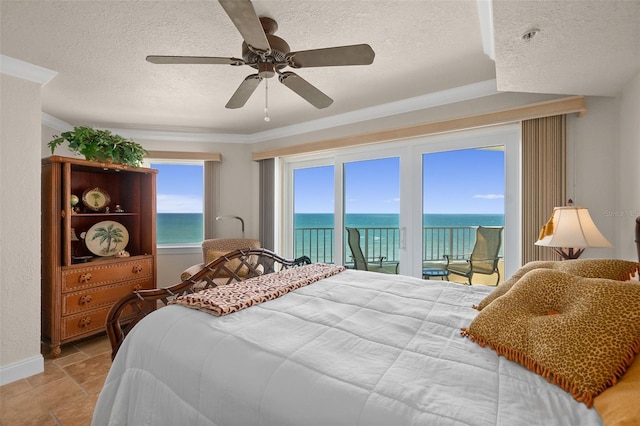 bedroom featuring access to outside, a water view, stone finish floor, a ceiling fan, and a textured ceiling