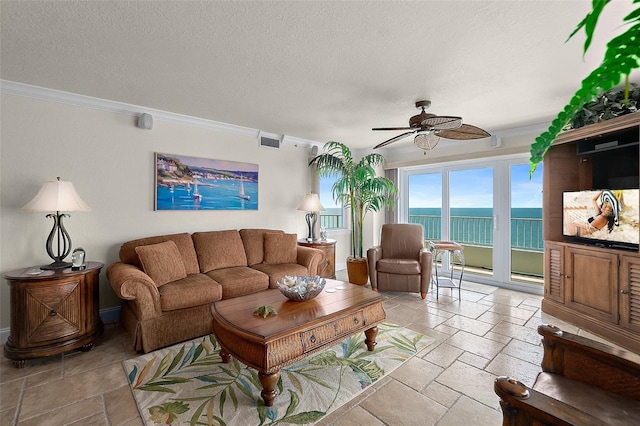living area with visible vents, ceiling fan, stone tile flooring, and crown molding