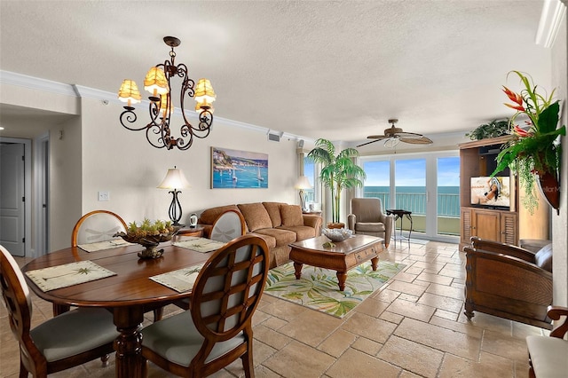 dining room featuring a textured ceiling, stone tile flooring, crown molding, and ceiling fan with notable chandelier