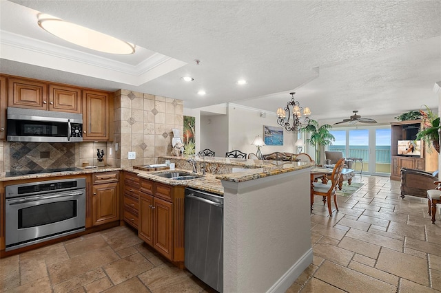 kitchen featuring stainless steel appliances, stone tile flooring, crown molding, and a sink