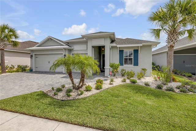 660 Mosaic Blvd, Daytona Beach, FL 32124 - view of front of home featuring stucco siding, an attached garage, a front yard, decorative driveway, and roof with shingles