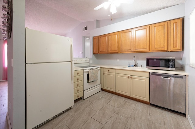 kitchen with appliances with stainless steel finishes, light countertops, vaulted ceiling, a sink, and visible vents
