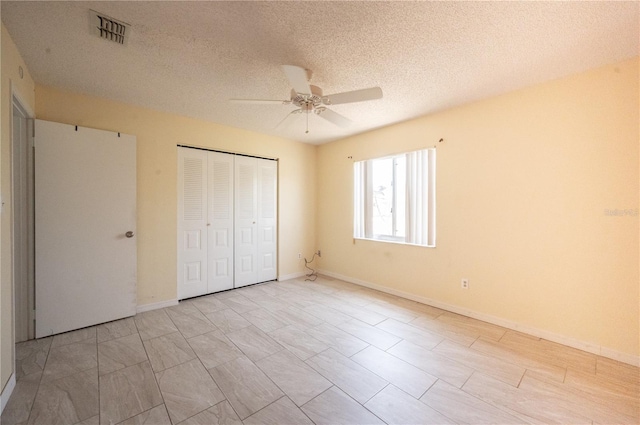 unfurnished bedroom with a closet, ceiling fan, visible vents, baseboards, and a textured ceiling
