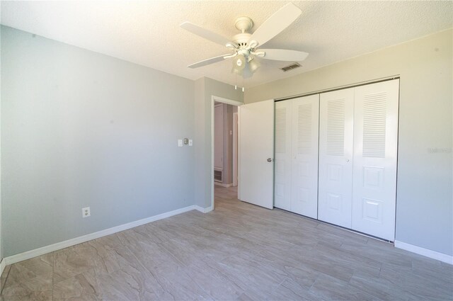 unfurnished bedroom with a closet, visible vents, a textured ceiling, and baseboards