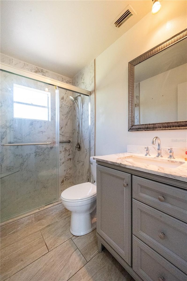 bathroom featuring toilet, a marble finish shower, visible vents, and vanity