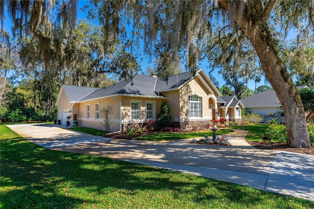 bungalow featuring concrete driveway, stone siding, an attached garage, a front yard, and stucco siding