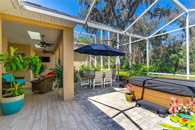 view of patio with a lanai, a hot tub, outdoor dining area, and ceiling fan