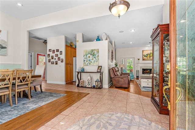 entryway featuring recessed lighting, a warm lit fireplace, and light tile patterned floors