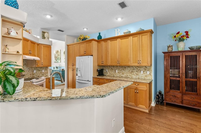 kitchen featuring under cabinet range hood, open shelves, visible vents, white appliances, and light stone countertops