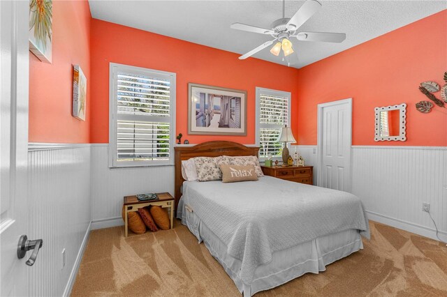 bedroom with wainscoting, baseboards, carpet, and ceiling fan