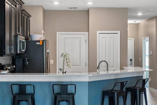 1079 Quaker Ridge Ln, Davenport, FL 33896 - kitchen featuring a breakfast bar, visible vents, stainless steel appliances, and light countertops