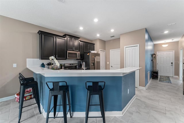 1079 Quaker Ridge Ln, Davenport, FL 33896 - kitchen featuring a kitchen bar, a peninsula, appliances with stainless steel finishes, and light countertops