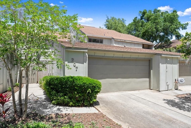 garage featuring fence and concrete driveway