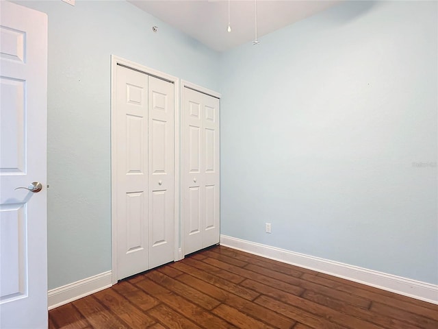 unfurnished bedroom with baseboards and dark wood-style floors