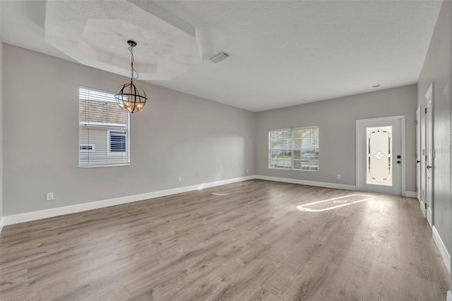 interior space with wood finished floors, an inviting chandelier, baseboards, visible vents, and a textured ceiling