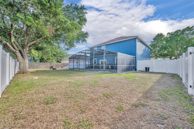 view of yard featuring a gate, glass enclosure, and a fenced backyard
