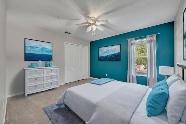 bedroom with a closet, ceiling fan, visible vents, baseboards, and a textured ceiling
