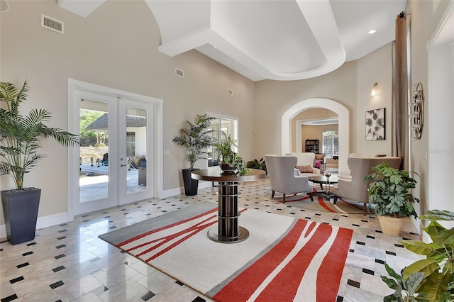foyer with french doors, arched walkways, a high ceiling, baseboards, and recessed lighting