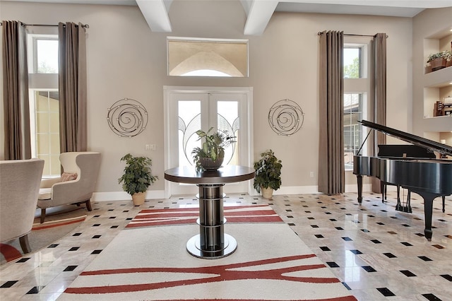 entrance foyer featuring light tile patterned floors, baseboards, french doors, and a towering ceiling