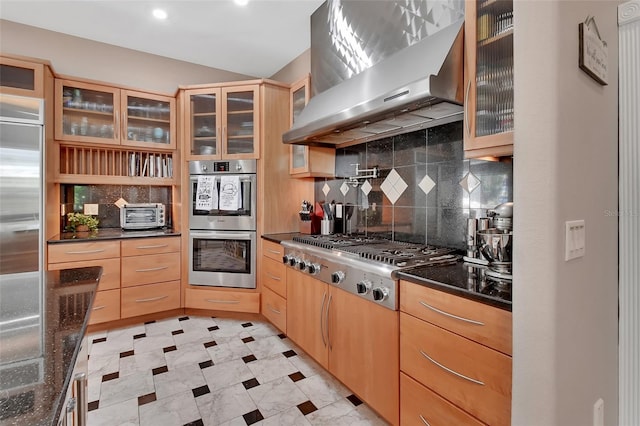 kitchen with wall chimney range hood, appliances with stainless steel finishes, decorative backsplash, light brown cabinetry, and recessed lighting