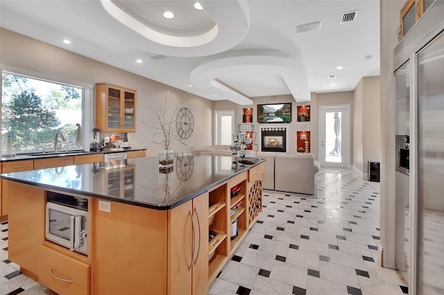 kitchen featuring a sink, open shelves, glass insert cabinets, a spacious island, and recessed lighting