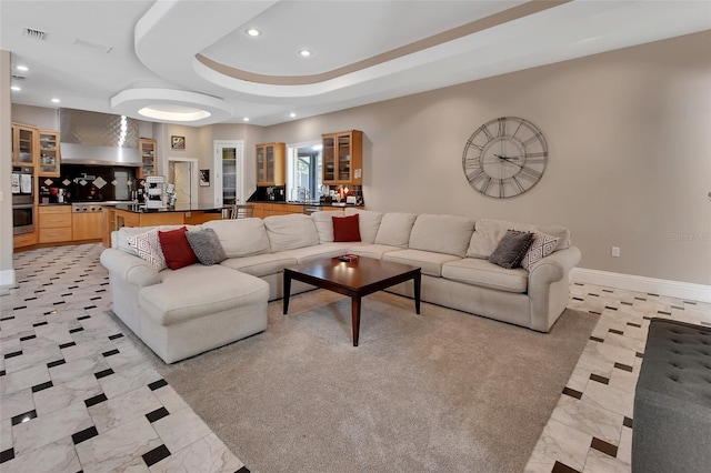 living room featuring recessed lighting, baseboards, and a raised ceiling