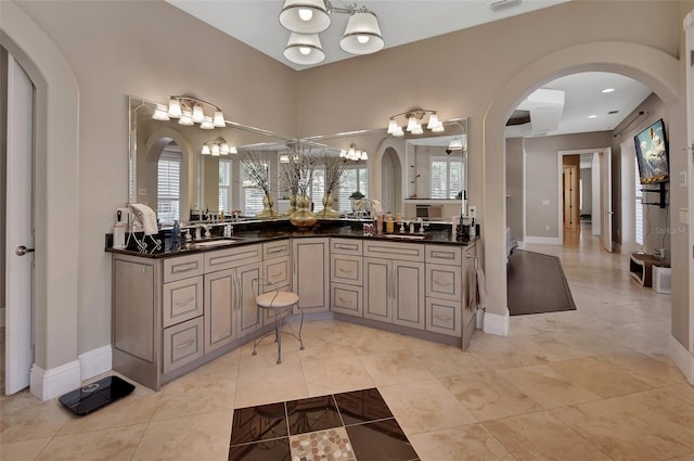 bathroom with a chandelier, tile patterned floors, double vanity, and baseboards