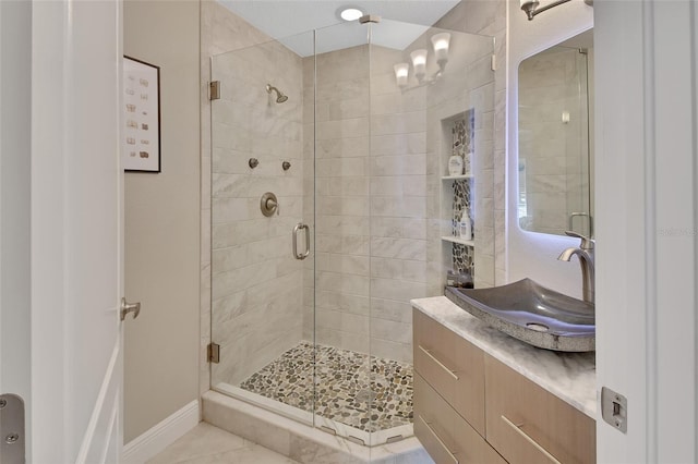 bathroom featuring a shower stall, vanity, tile patterned floors, and baseboards