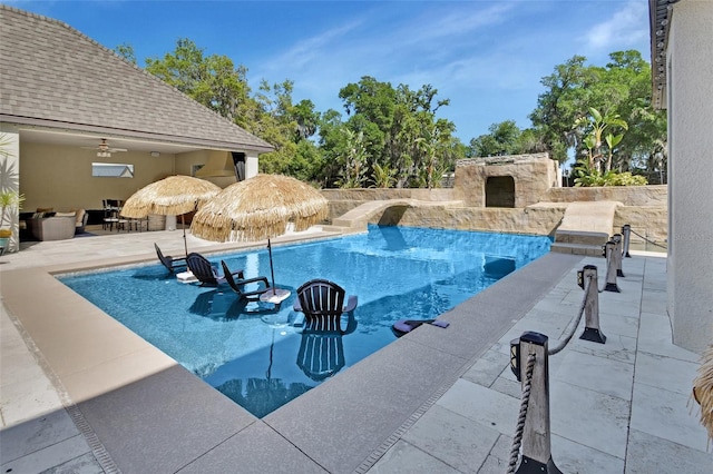 outdoor pool featuring an outdoor stone fireplace and a patio area