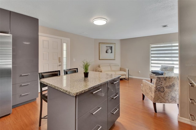kitchen with a breakfast bar, high end refrigerator, modern cabinets, and light wood-style floors