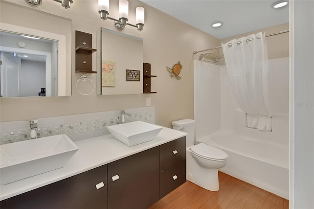 bathroom featuring wood finished floors, shower / bath combo with shower curtain, toilet, and double vanity