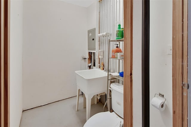 half bathroom featuring electric panel, toilet, and concrete floors