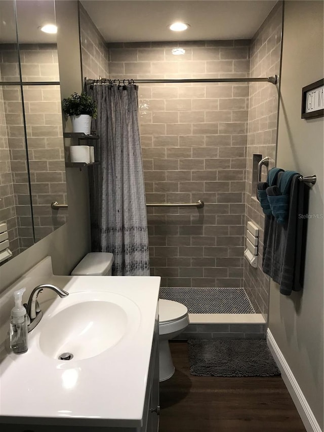 bathroom with toilet, wood finished floors, a stall shower, vanity, and recessed lighting